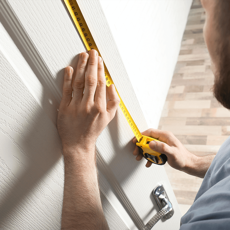 A person measuring a door with a tape measure